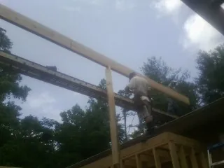 Carpenter setting a ridge beam over a new addition frame — Ice Dam Removal by Roofing Brothers in Lower Salem