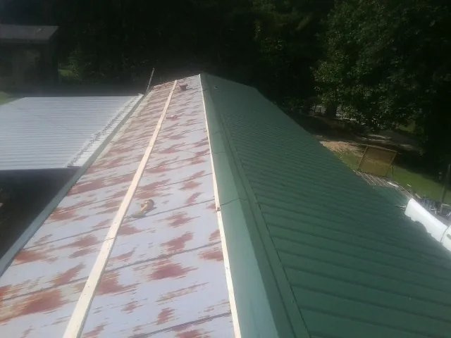 Old rusted panels beside newly installed green metal roofing — Wind Damage Roof Repair by Roofing Brothers in Lower Salem