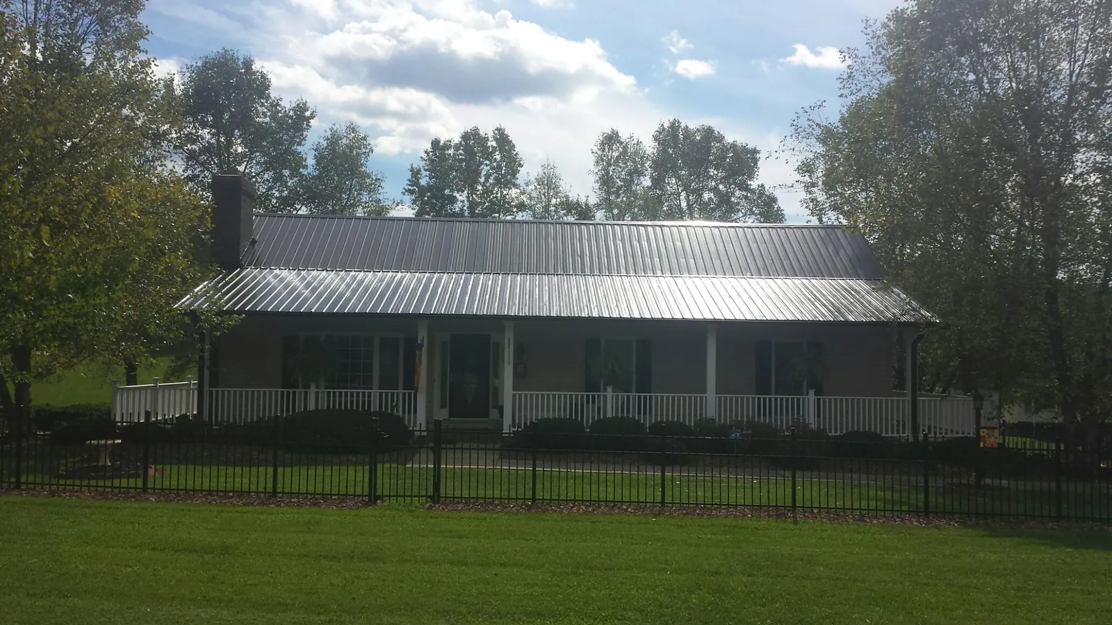 Gray metal roof on a brick ranch with a full width front porch — Gutter Guard Installation work by our crew in Lower Salem