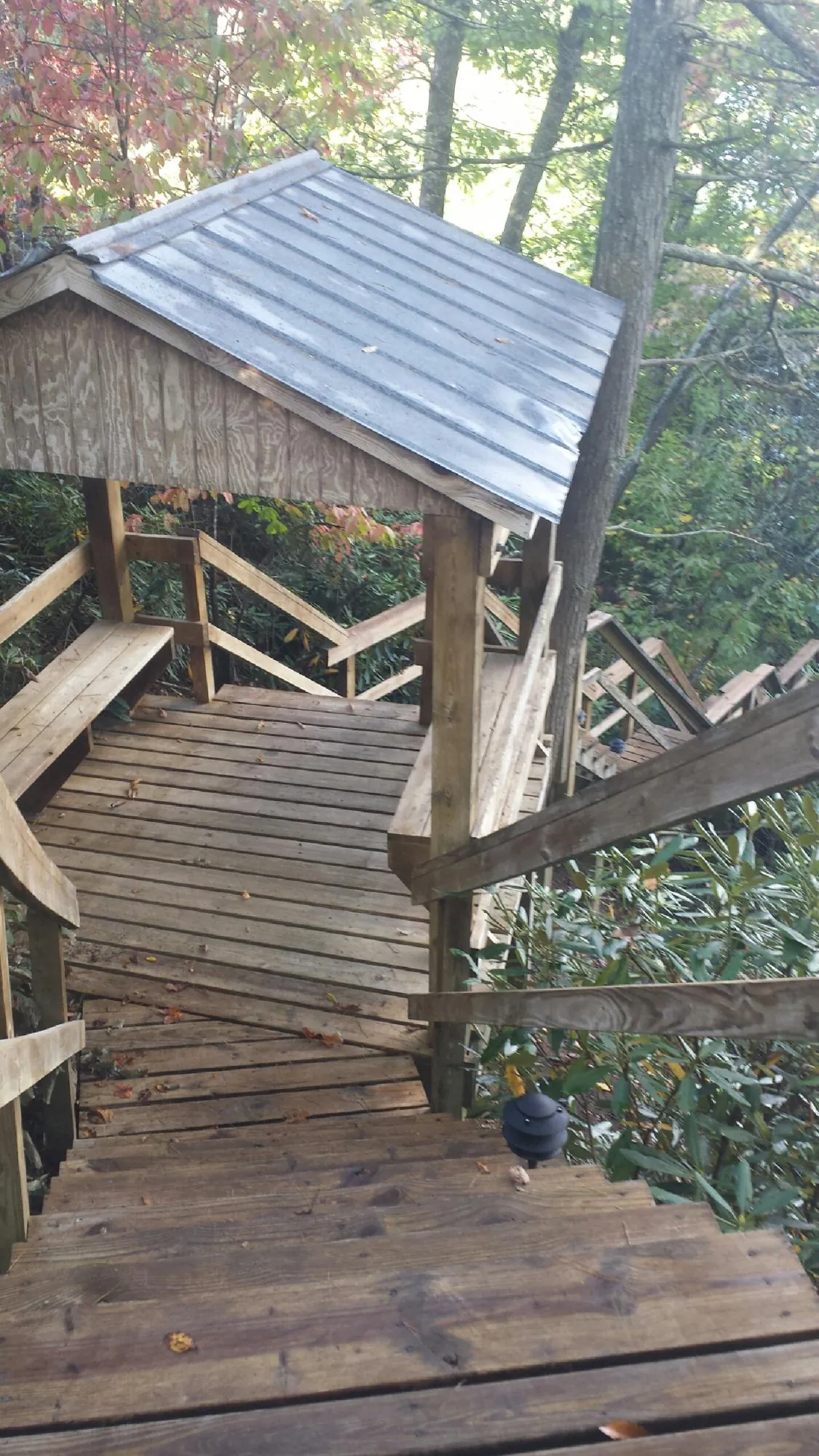 Metal roofed shelter over wooden steps on a wooded walkway — Skylight Repair & Installation work by our crew in Lower Salem