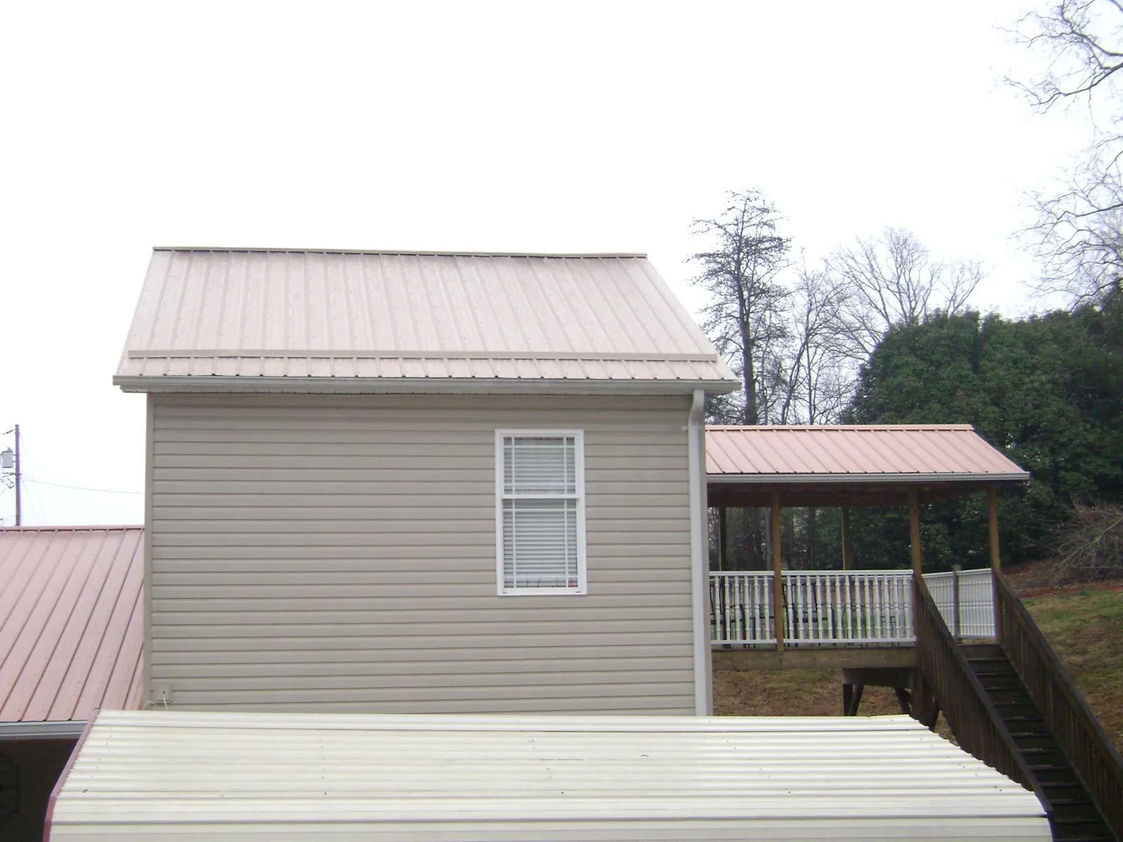 Tan metal roofs on a two story addition and attached porch, from a Roof Replacement job in Lower Salem