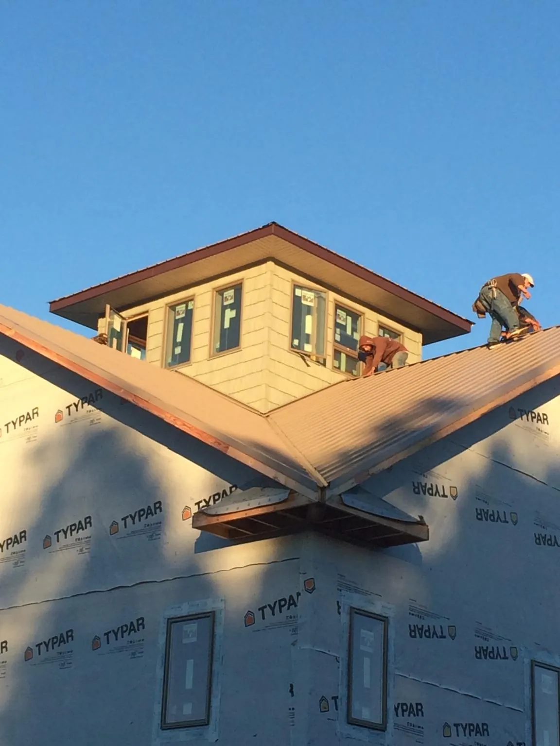 Roofers working around a rooftop cupola on a new metal roof at sunset — Roof Waterproofing in Lower Salem by Roofing Brothers